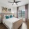 a bedroom with a bed, natural light and a fan