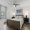 a bedroom with a bed, connected bathroom, ceiling fan and a window